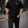 man wearing black oversized t-shirt with minimal logo modern streetwear style